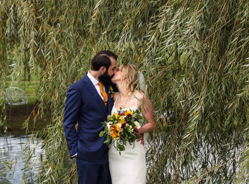 Bride and groom kissing beside a willow tree by the Pocomoke River